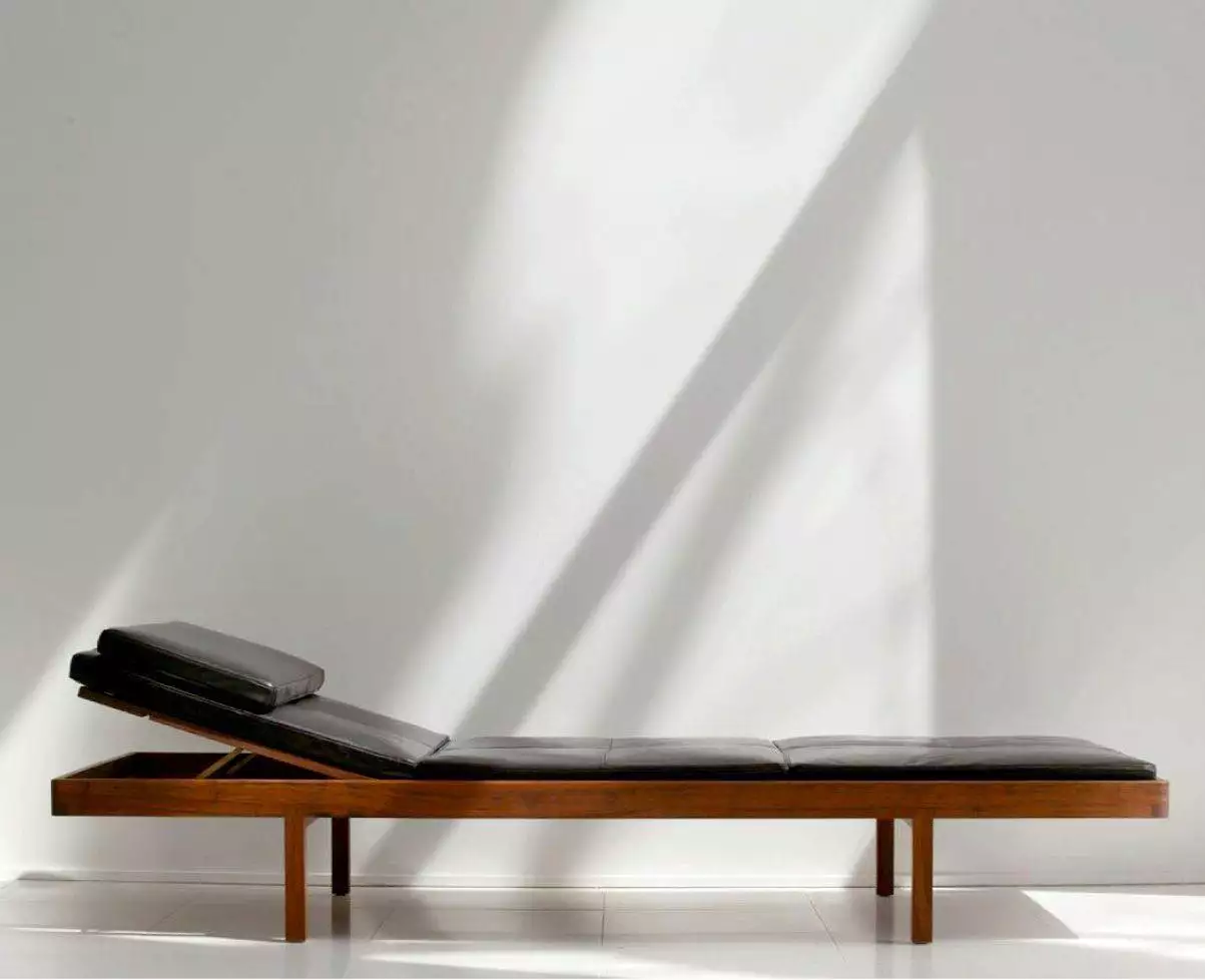 A modern chaise lounge with a black leather seat by Bassam Fellows.