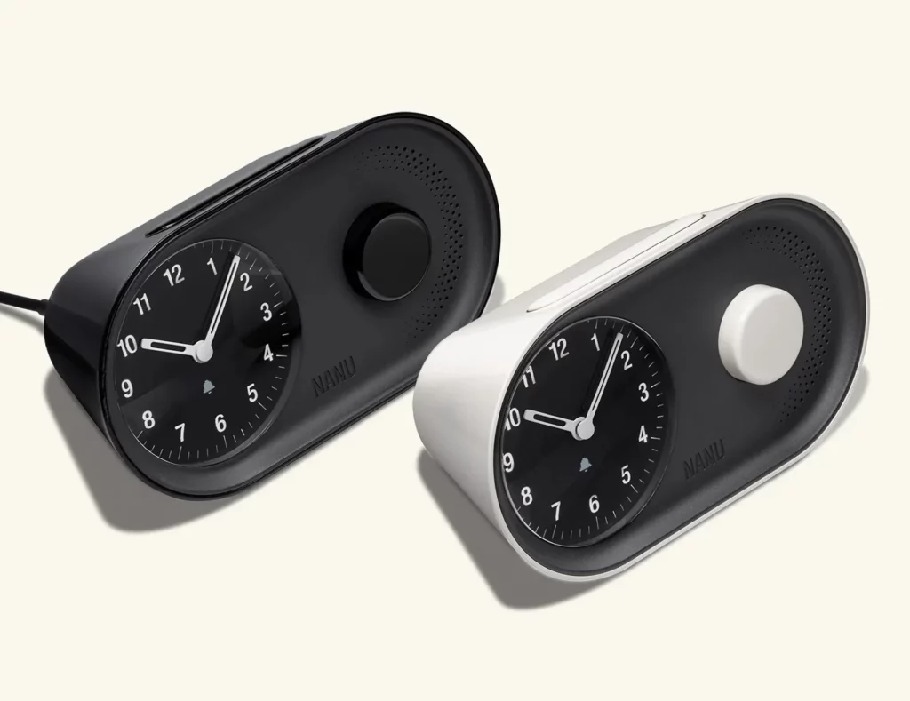 Two modern analog alarm clocks, one black and one white, with round dials and minimalist design—perfect for intentional living and elevating your time management routine.