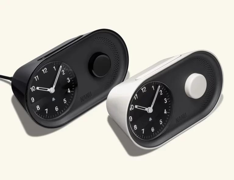 Two modern analog alarm clocks, one black and one white, with round dials and minimalist design—perfect for intentional living and elevating your time management routine.